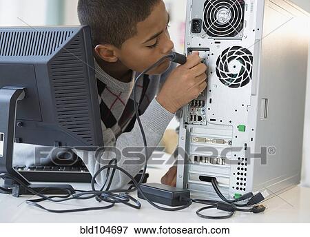 Stock Photo - Hispanic boy plugging in computer. Fotosearch