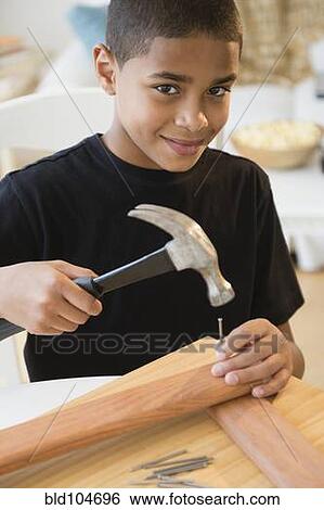 Stock Photograph - Hispanic boy using hammer and nails. Fotosearch