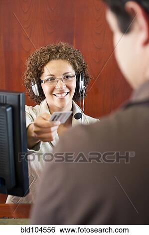 Hispanic businesswoman in headset handing credit card to customer View Large Photo Image Stock Photograph - Hispanic businesswoman in headset handing credit card to customer. Fotosearch
