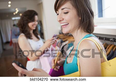 Stock Image - Hispanic friends shopping in clothing store. Fotosearch