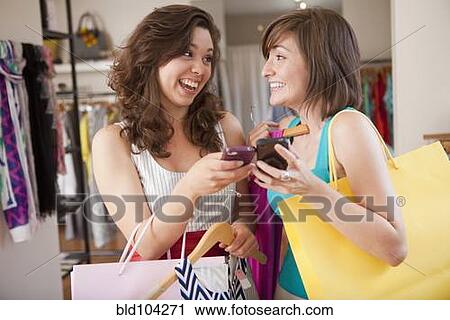 Stock Image - Hispanic friends shopping in clothing store. Fotosearch