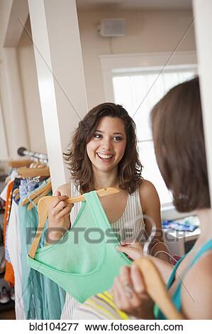 Stock Photo - Hispanic friends shopping in clothing store. Fotosearch