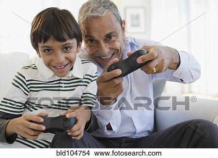 Picture - Hispanic grandfather and grandson playing video game. Fotosearch