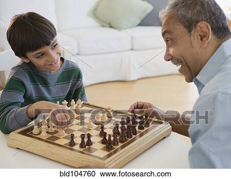 Stock Image - Hispanic grandfather and grandson playing chess. Fotosearch