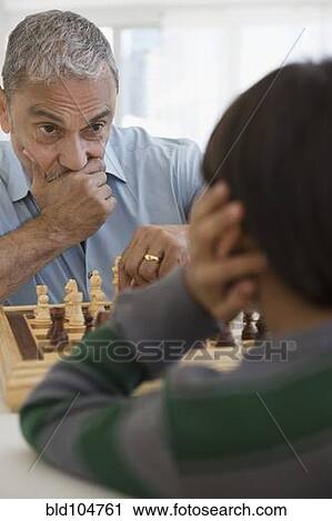 Stock Image - Hispanic grandfather and grandson playing chess. Fotosearch