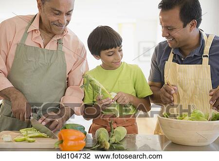 Stock Image - Hispanic grandfather, father and son preparing food. Fotosearch