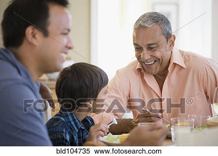 Stock Photography - Hispanic grandfather, father and son eating dinner. Fotosearch
