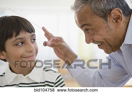 Stock Photo - Hispanic grandfather offering coin to grandson. Fotosearch