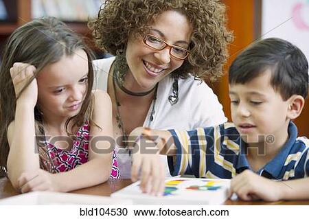 Stock Image - Hispanic teacher helping students. Fotosearch