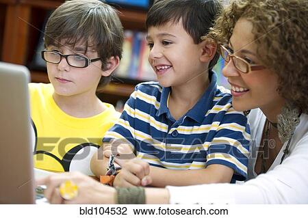 Stock Image - Hispanic teacher helping students. Fotosearch