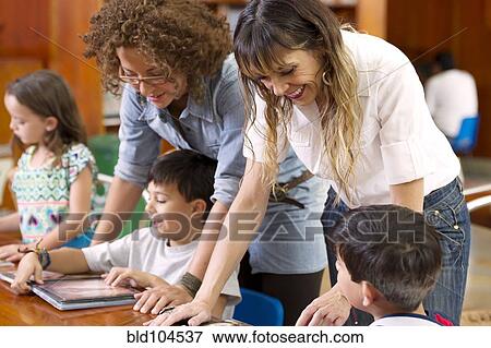 Stock Photo - Hispanic teachers helping students. Fotosearch