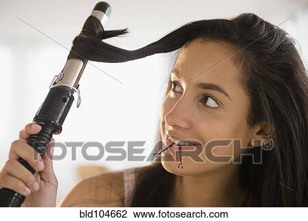 Stock Image - Hispanic teenager curing her hair. Fotosearch