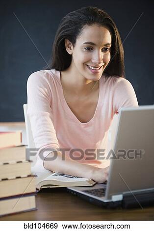 Stock Photo - Hispanic teenager doing homework on laptop. Fotosearch