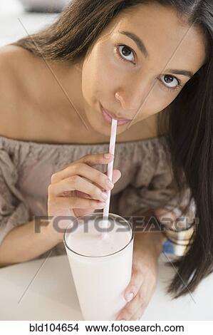 Picture - Hispanic teenager drinking milk with straw. Fotosearch