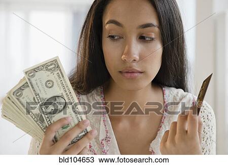 Stock Image - Hispanic teenager holding credit cards and money. Fotosearch