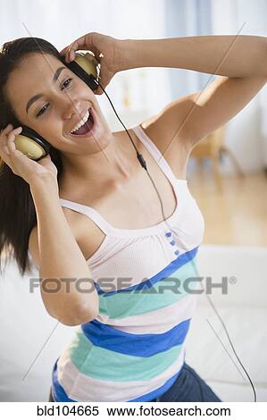 Stock Photography - Hispanic teenager listening to music on headphones. Fotosearch