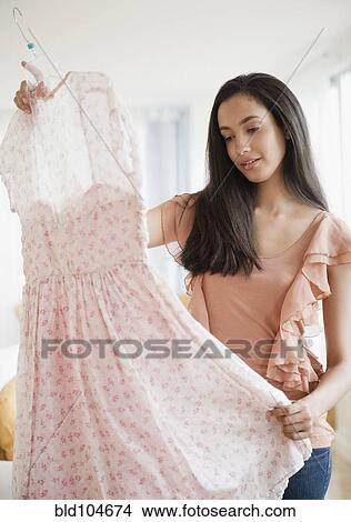 Picture - Hispanic teenager looking at dress. Fotosearch