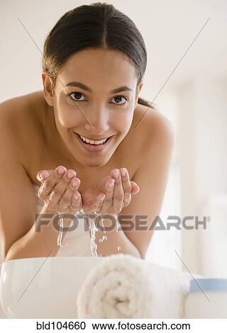Stock Image - Hispanic teenager washing her face. Fotosearch
