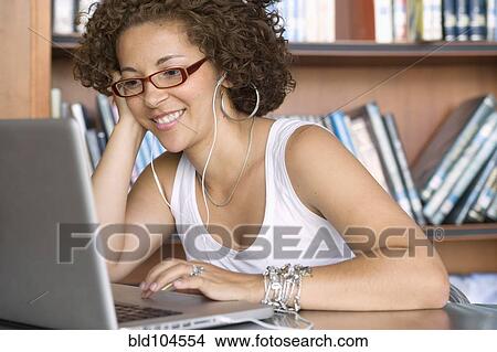 Picture - Hispanic woman using laptop in library. Fotosearch