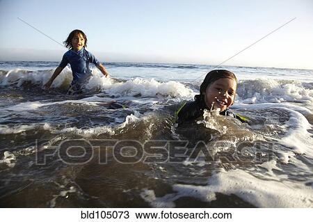 Stock Image - Mixed race boys swimming in ocean. Fotosearch