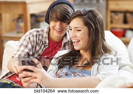 Mixed race friends looking at cell phone View Large Photo Image Picture - Mixed race friends looking at cell phone. Fotosearch