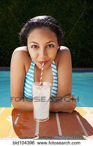 Stock Photograph - Mixed race girl drinking lemonade near swimming pool. Fotosearch