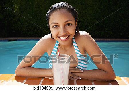Stock Photography - Mixed race girl drinking lemonade near swimming pool. Fotosearch