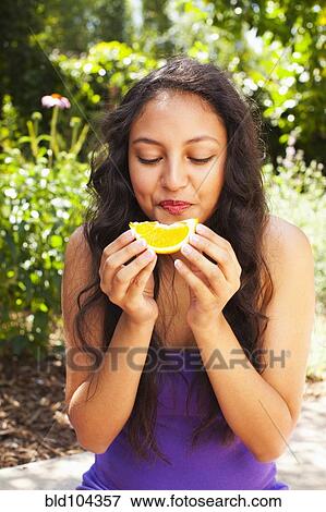 Stock Photo - Mixed race teenager eating orange. Fotosearch