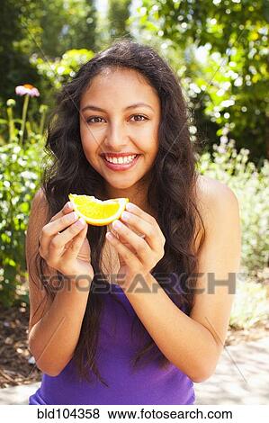 Stock Photo - Mixed race teenager eating orange. Fotosearch