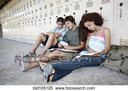 Stock Image - School friends doing homework together near lockers. Fotosearch