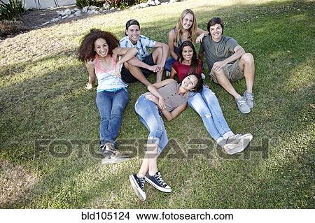 Picture - School friends sitting together in grass. Fotosearch