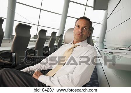 Stock Photo - Serious Caucasian businessman sitting in conference room. Fotosearch