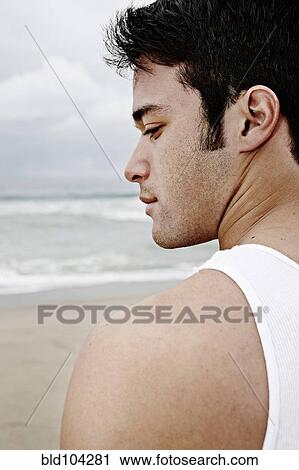 Stock Image - Serious young man on beach. Fotosearch
