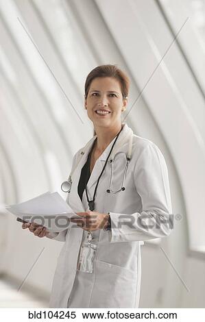 Stock Photography - Smiling Caucasian doctor standing in hospital corridor. Fotosearch