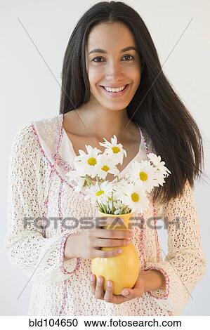 Stock Image - Smiling Hispanic teenager holding flowers. Fotosearch