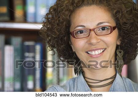 Stock Image - Smiling Hispanic woman in library. Fotosearch