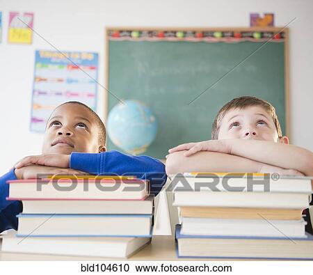Students leaning on stacks of books in classroom View Large Photo Image Stock Image - Students leaning on stacks of books in classroom. Fotosearch