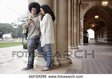 Students looking at cell phone together View Large Photo Image Stock Photo - Students looking at cell phone together. Fotosearch