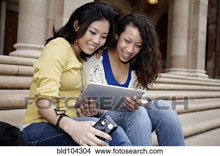 Picture - Students looking at digital tablet together. Fotosearch
