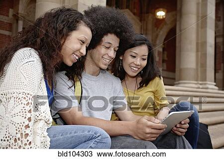 Stock Image - Students looking at digital tablet together. Fotosearch
