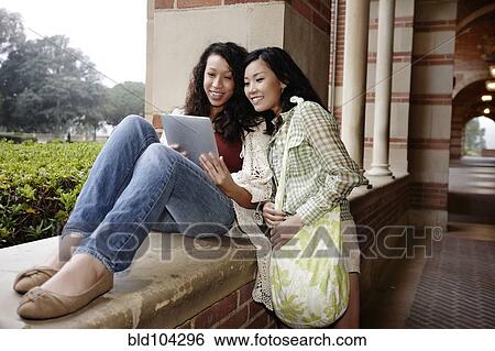 Stock Photograph - Students looking at digital tablet together. Fotosearch