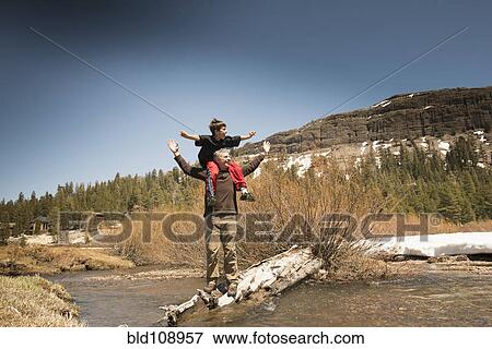 Boy sitting on father's shoulders in creek View Large Photo Image Stock Photo - Boy sitting on father's shoulders in creek. Fotosearch