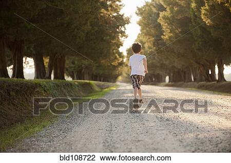 Stock Image - Caucasian boy running on dirt road. Fotosearch