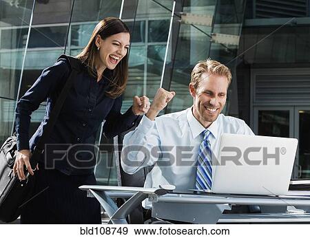 Stock Photo - Caucasian business people cheering at laptop. Fotosearch