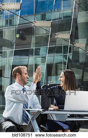 Caucasian business people high fiving at desk View Large Photo Image Stock Image - Caucasian business people high fiving at desk. Fotosearch