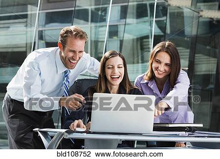 Stock Image - Caucasian business people watching laptop. Fotosearch