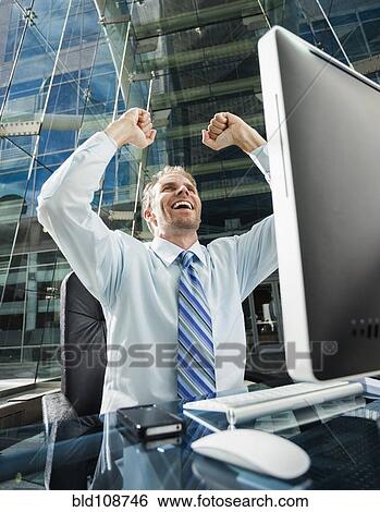 Caucasian businessman cheering at computer View Large Photo Image Stock Photograph - Caucasian businessman cheering at computer. Fotosearch