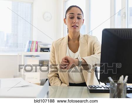 Caucasian businesswoman checking watch at desk View Large Photo Image Stock Photo - Caucasian businesswoman checking watch at desk. Fotosearch