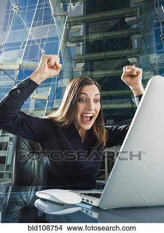 Caucasian businesswoman cheering at computer View Large Photo Image Picture - Caucasian businesswoman cheering at computer. Fotosearch