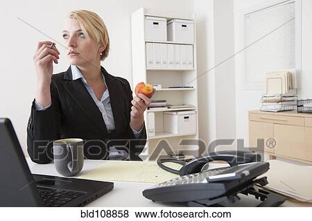 Caucasian businesswoman eating at desk in office View Large Photo Image Stock Photo - Caucasian businesswoman eating at desk in office. Fotosearch